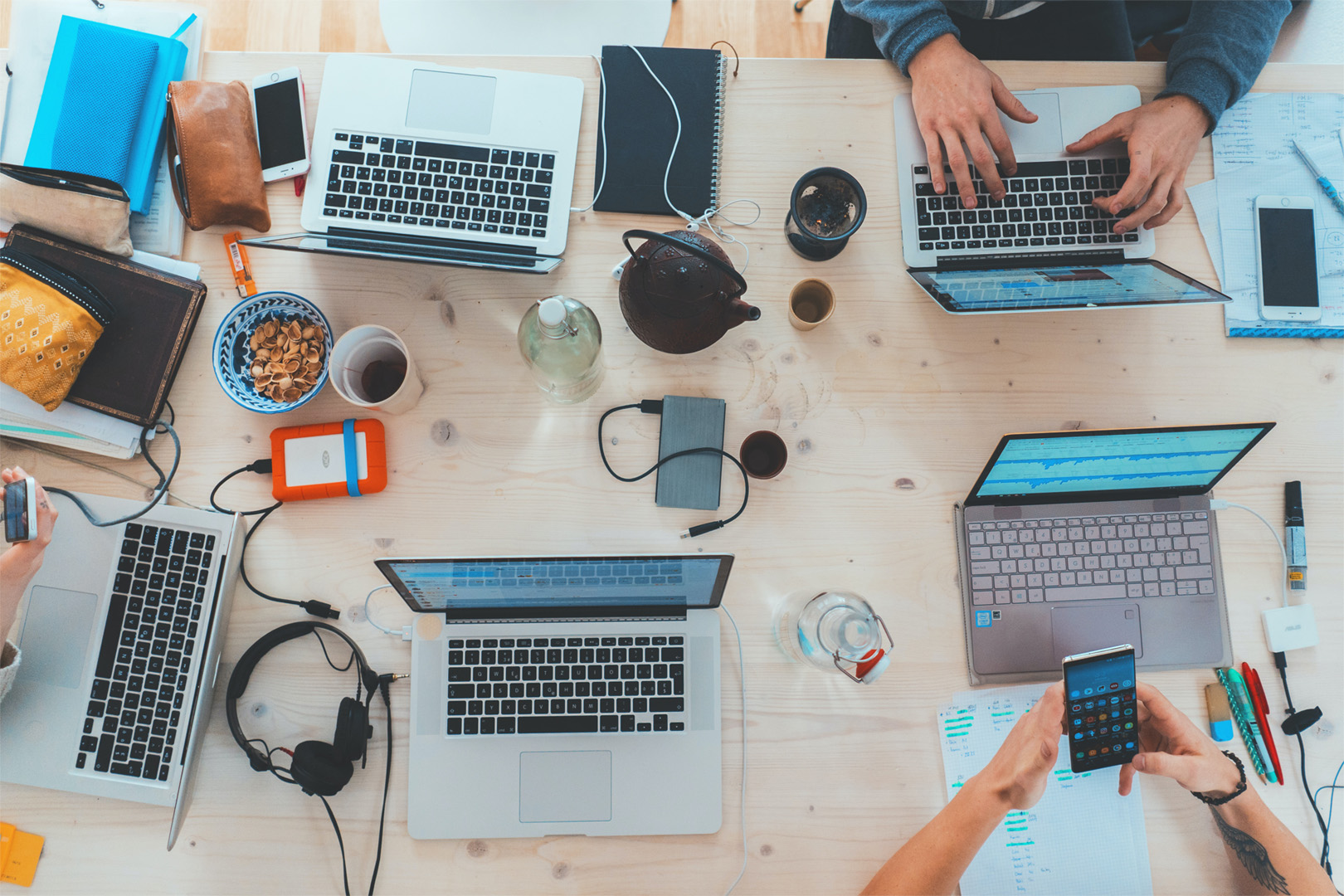 Decorative: Desk with multiple laptops on it and people working