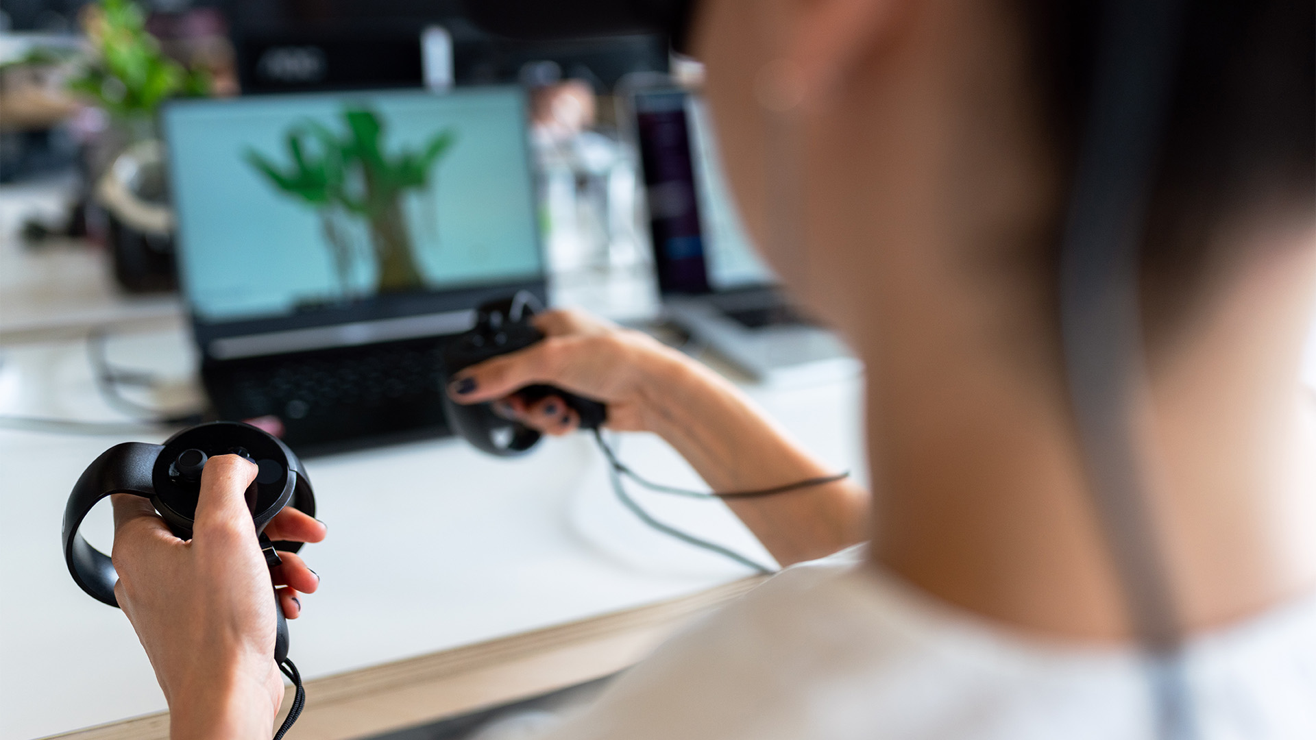 Decorative image: a person holding black controllers in front of a laptop