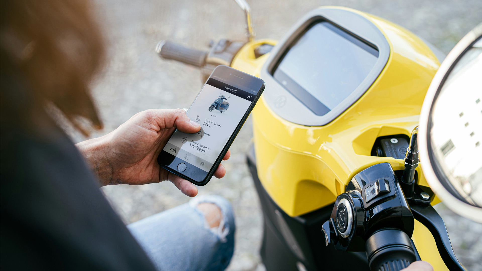 decorative: a person holding a phone that has information about the scooter they are sitting on