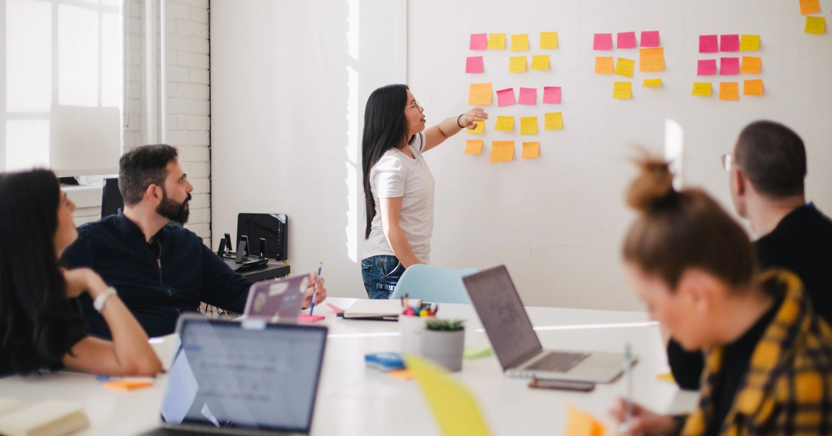 Image of a woman adding a sticky note to a wall